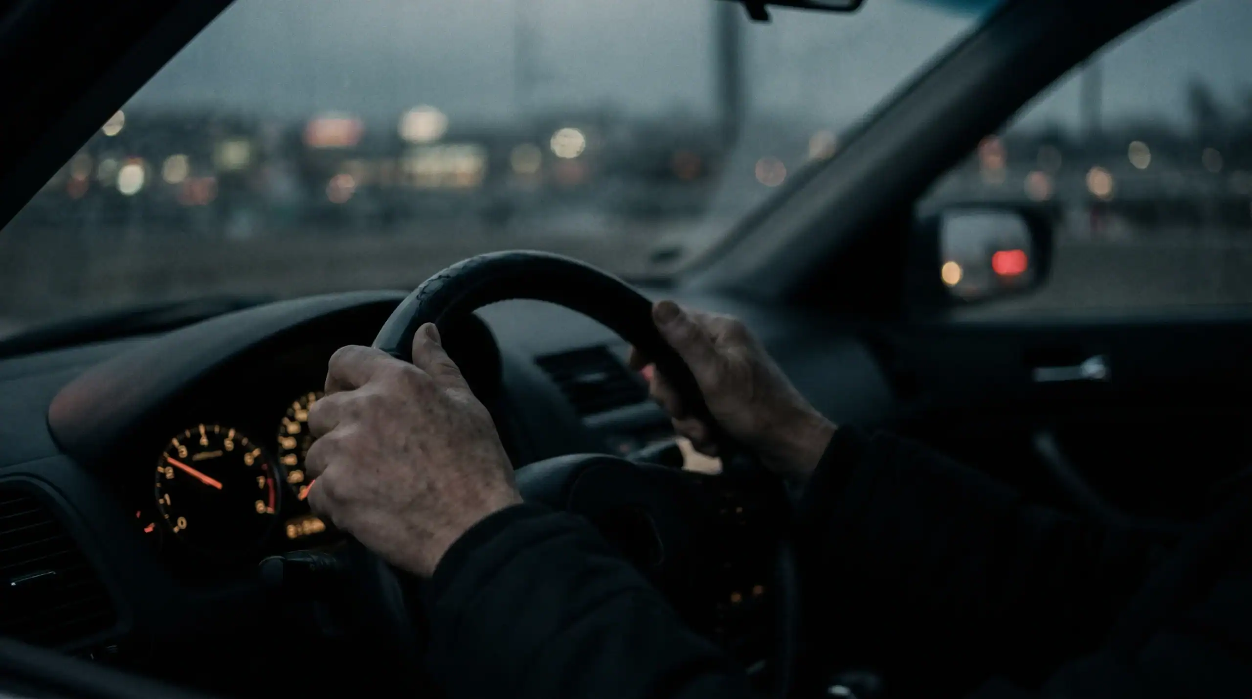 Ruke na volanu u sumrak, cesta izvan fokusa, vožnja na autopilotu